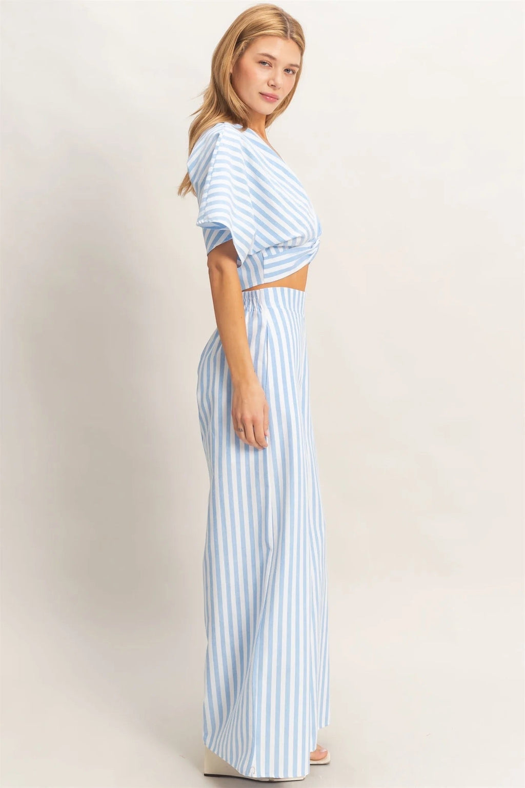 Discover a chic two-piece set featuring a twist front top with a low V-neckline and relaxed short sleeves. Complemented by high-waist wide-leg pants, this ensemble combines a striking striped pattern with a flowing silhouette. Pair with sleek sandals for a polished summer outfit.